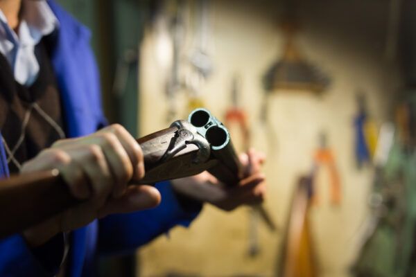 An open double-barreled gun in the hands of a gunsmith.